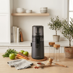 Hurom H70 cold press juicer on a kitchen counter next to fresh fruits and vegetables