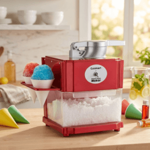 Red Cuisinart Snow Cone Maker on a clean white textured background, featuring a built-in clear bin filled with shaved ice, a silver mechanical press handle on top, and a side tray holding one red and one blue snow cone in white paper cones.